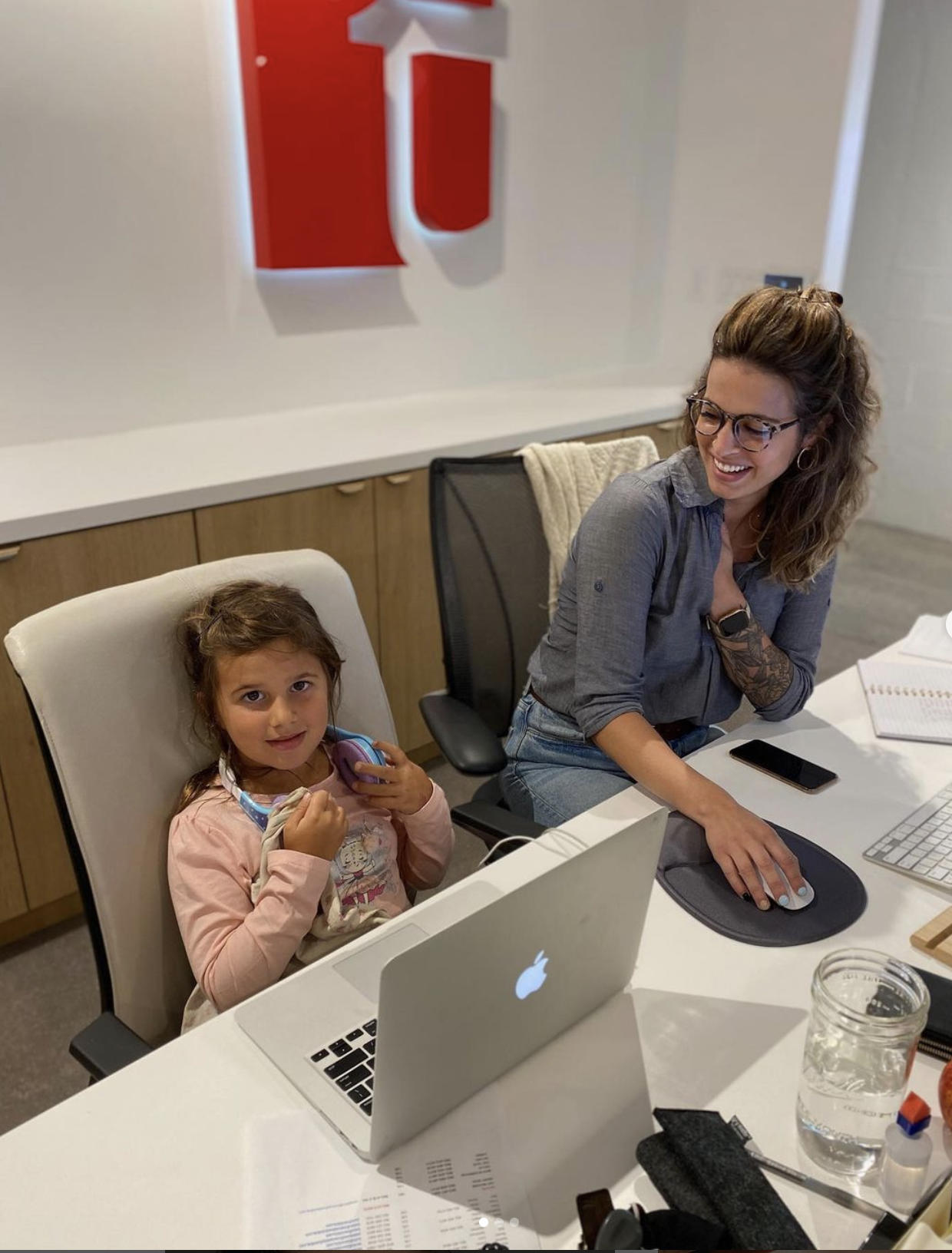 Female office manager at her desk with her young daughter