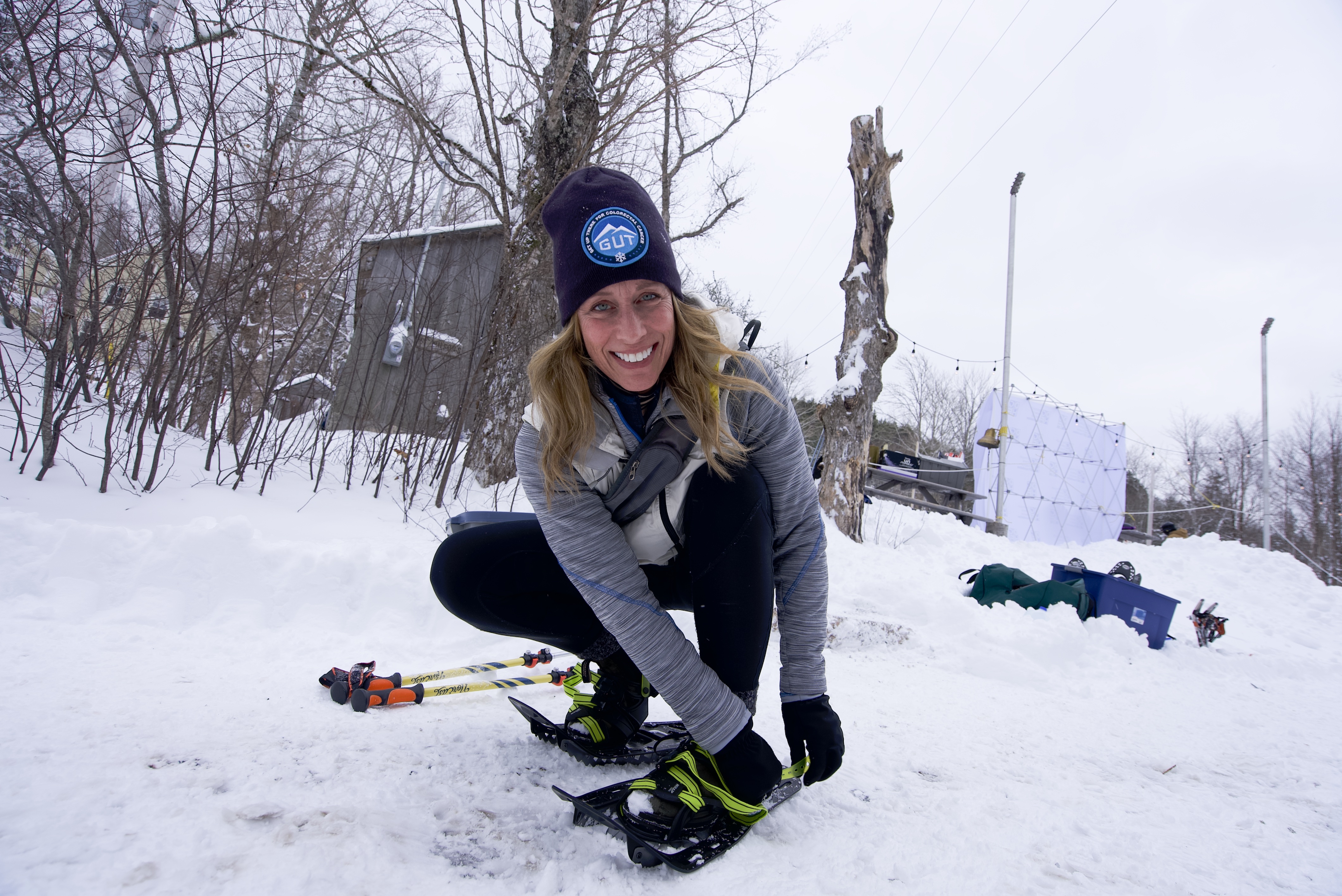 Picture shows a woman putting a ski on in the snow