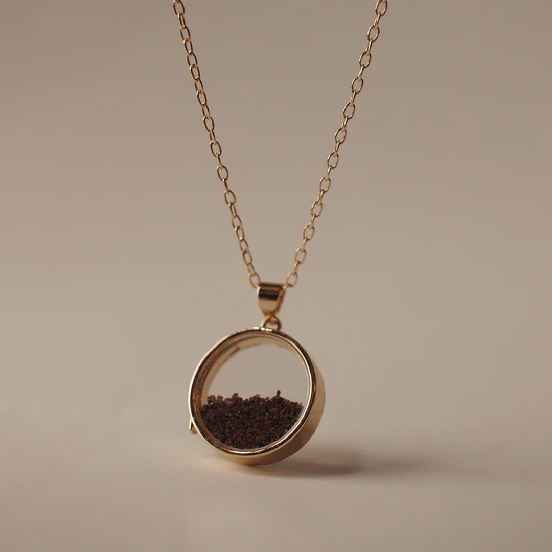 Golden necklace pendant with brown sand inside