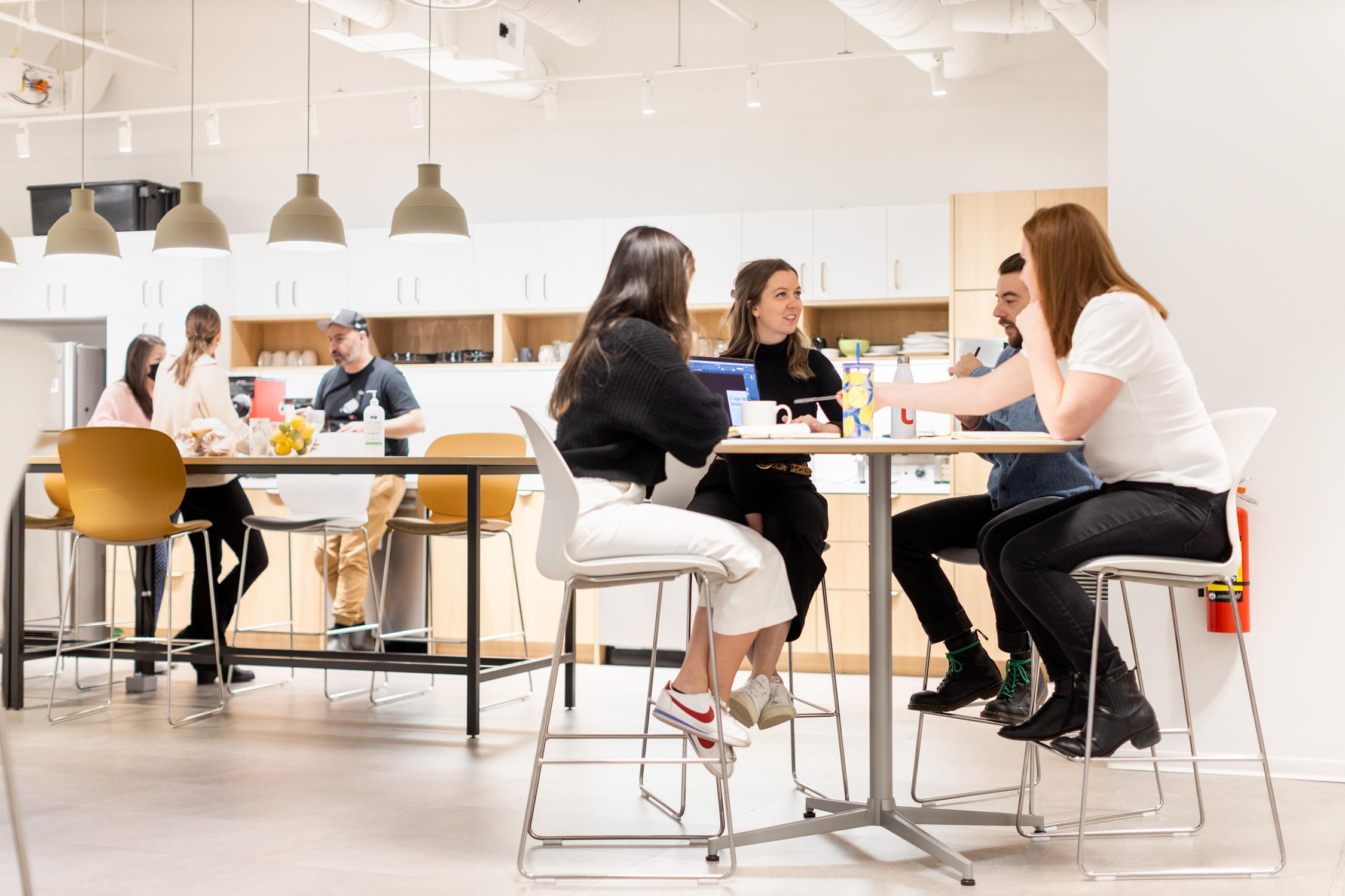 Four young professionals sitting working in the kitchen